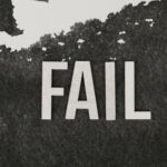 Grayscale image of the word 'FAIL' on a textured, monochrome background.