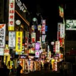 Explore Seoul's vibrant nightlife on a bustling neon-lit street lined with shops and restaurants.