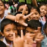 A joyful group of children smiling and making playful gestures outdoors in Namarjung, Nepal.