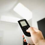 Close-up of a man using a remote to control air conditioning indoors.