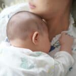 A newborn baby peacefully sleeps on the mother's chest, capturing a tender moment of love and comfort.